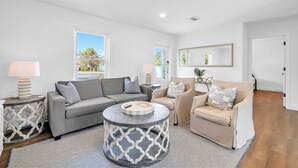 Ein modernes Wohnzimmer mit einem grauen Sofa, einem beigefarbenen Sessel und einem runden Couchtisch.