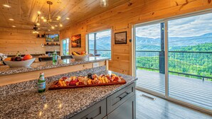 A kitchen with granite countertops, wooden ceiling, and large windows with a mountain view. - Luxury Panoramic Mountain Views - DT Gatlinburg, Theater&PoolT, Hot Tub, Dogs (Gatlinburg)