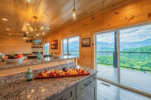 Eine Küche mit Granit-Arbeitsplatten, Holzboden und großen Fenstern mit Blick auf die Berge.