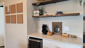 Een keuken met een ingebouwde oven, een koffiehoek en een prikbord met aantekeningen.