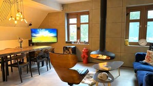 A modern living room with a fireplace, a dining area, and a sofa.