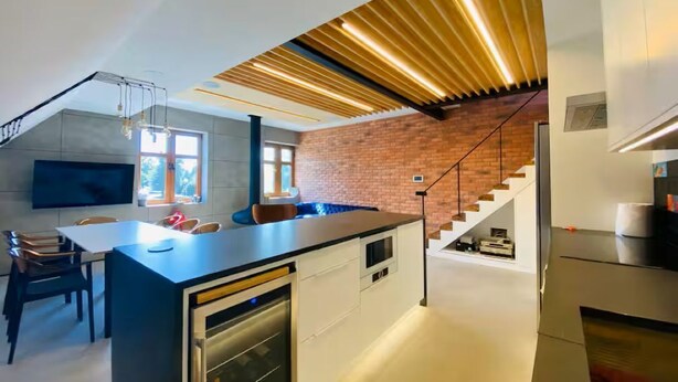 A modern kitchen with a central island, built-in appliances, and a staircase leading to an upper level.