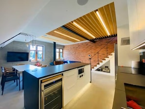 Cocina moderna con una isla central, electrodomésticos integrados y una escalera que lleva a un nivel superior.
