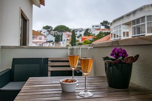 A table with two glasses of a clear liquid, a small bowl of nuts, and a potted plant with purple flowers. - Parede Coastal Family Retreat (Cascais)
