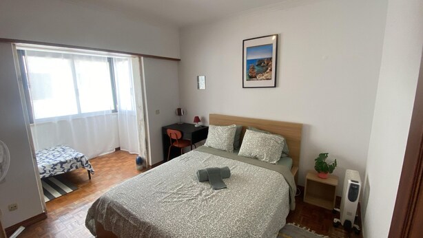 A bedroom with a bed, a desk, a chair, a radiator, and a window. - Parede Coastal Family Retreat (Cascais)