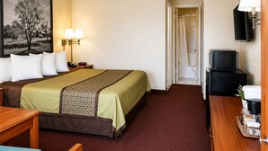 A hotel room with a bed, bedside lamps, a television, a desk, and a chair. - Truestay Inn (Bakersfield)