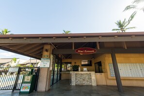 A hotel reception area with a registration desk, a sign for the Maui Kamaole Information, and a glass door entrance. - Ocean View Maui Kamaole Condo | 2 Pools, Hot Tub, Ground Floor, Sleeps 4 (Kihei)