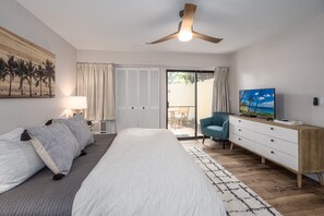 A bedroom with a bed, a ceiling fan, a TV, a dresser, and a view of the outside. - Ocean View Maui Kamaole Condo | 2 Pools, Hot Tub, Ground Floor, Sleeps 4 (Kihei)