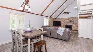 A spacious living area with a fireplace, a television, and a dining table with chairs. - Coastal Retreat, Modern Home Near Beach! (Fort Pierce)