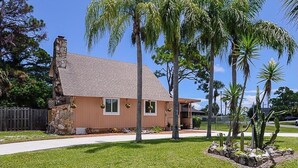 A single-story house with a stone chimney, a front porch, and a well-maintained lawn. - Coastal Retreat, Modern Home Near Beach! (Fort Pierce)