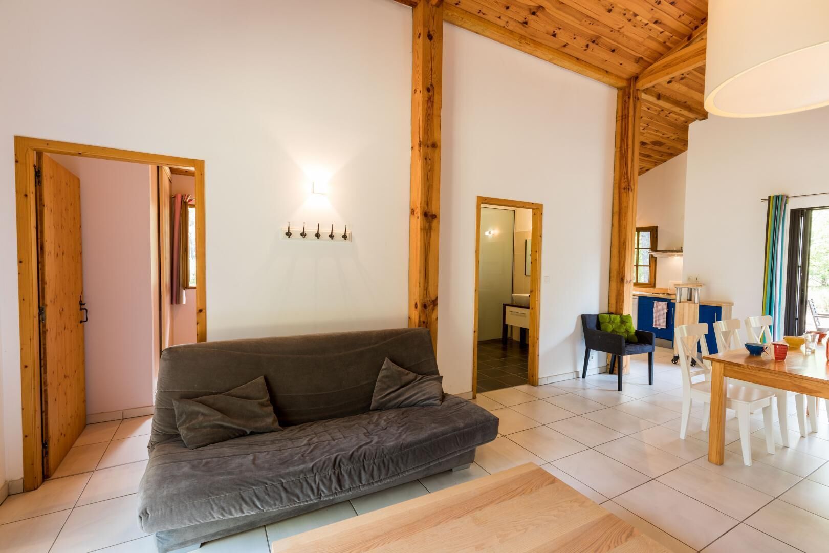 Een woonkamer met een bank, een eettafel, en een keuken die door een open deur zichtbaar is.