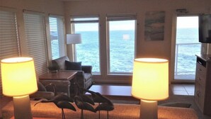 A room with a view of the sea, a sofa, two lamps, and a decorative bird sculpture. - CRASHING WAVES AND WHALES! (Depoe Bay)