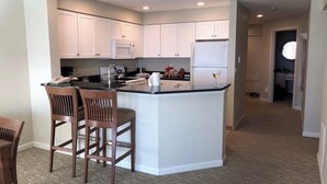 A modern kitchen with white cabinets, a central island, and bar stools. - CRASHING WAVES AND WHALES! (Depoe Bay)