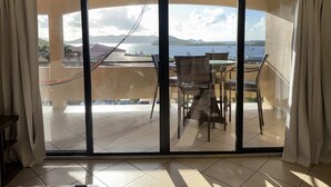 A room with a large sliding glass door leading to an outdoor terrace with a view of the sea and mountains. - Red Hook Retreat with Stunning Ocean Views (Red Hook)