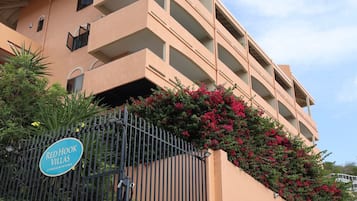 A multi-story building with balconies, a gated entrance, and a sign indicating 'Red Hook Villas'.
