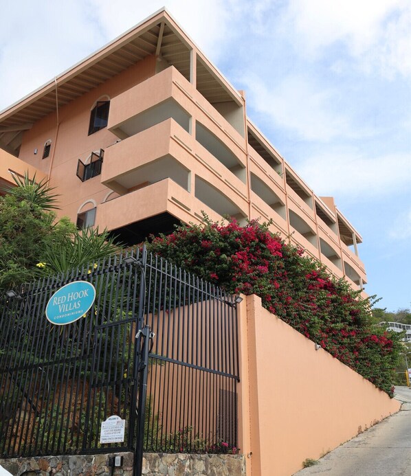 A multi-story building with balconies, a gated entrance, and a sign indicating 'Red Hook Villas'. - Red Hook Retreat with Stunning Ocean Views (Red Hook)