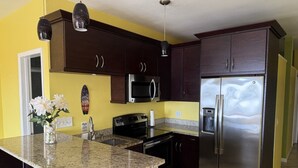 A kitchen with dark wooden cabinets, stainless steel appliances, and a granite countertop. - Red Hook Retreat with Stunning Ocean Views (Red Hook)