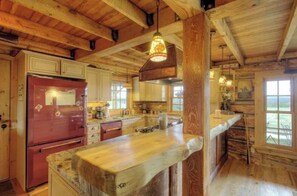 Eine rustikale Küche mit Holzbalken, einem roten Kühlschrank und einer großen Kücheninsel.