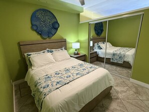 Ein Schlafzimmer mit Bett, Nachttischen, einem Spiegel und einem Wanddekor.