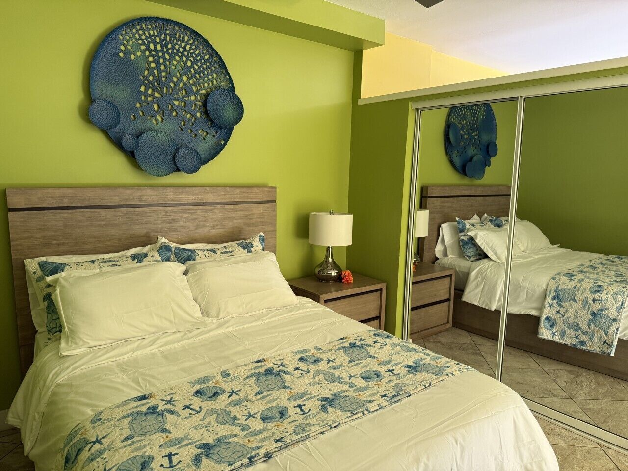 Une chambre d’hôtel avec un grand lit, une table de chevet, un miroir et un élément décoratif mural.