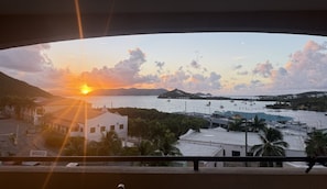 Sonnenuntergangblick von einem Balkon mit Blick auf einen Yachthafen, Parkplatz und Gebäude.
