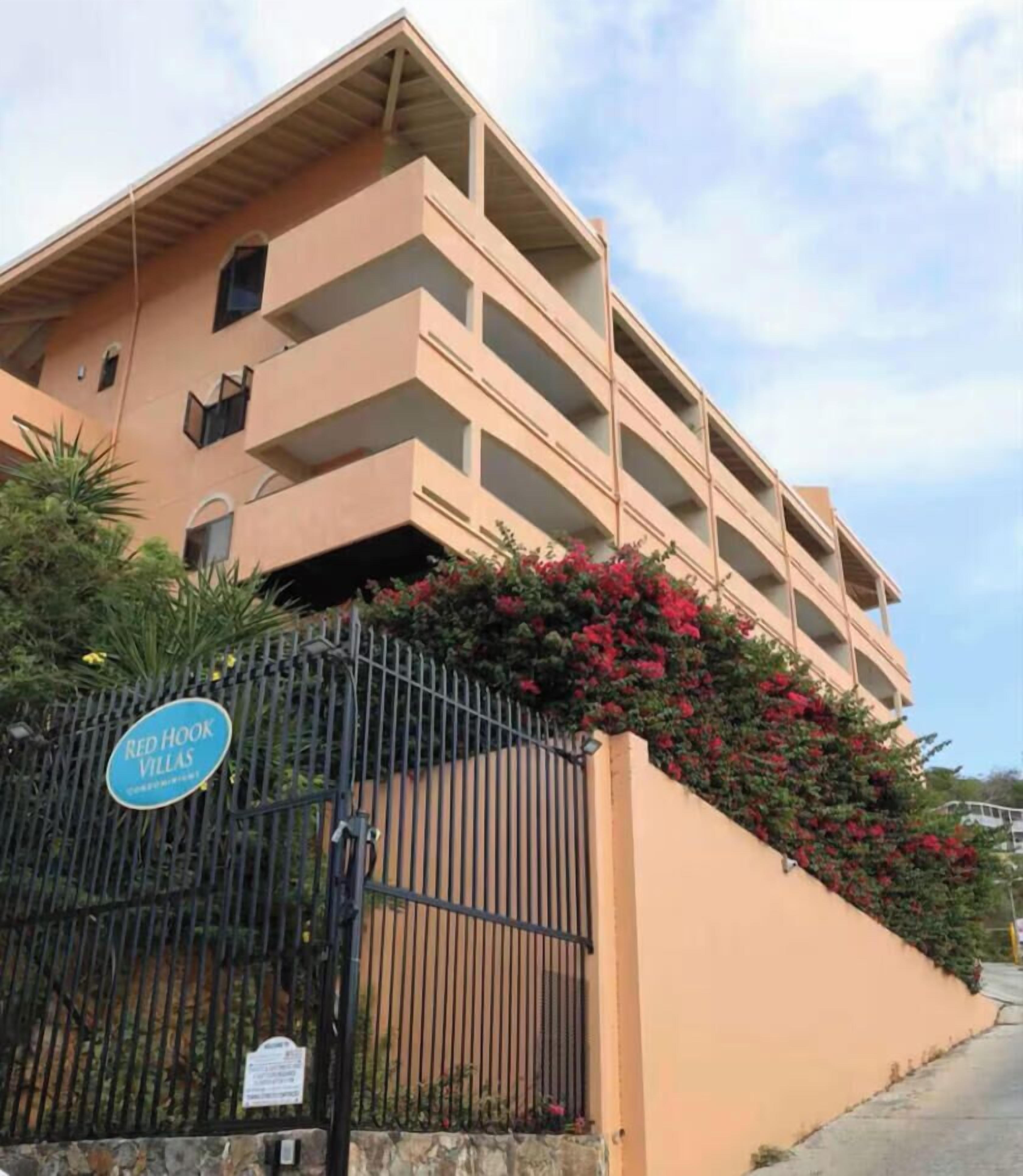 A multi-story building with balconies, a gated entrance, and a sign indicating 'Red Hook Villas.'