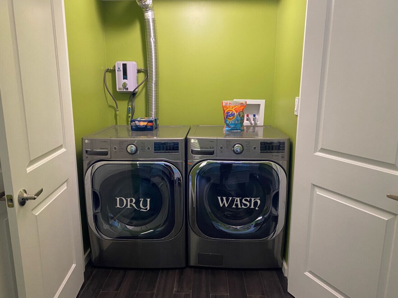 A laundry area with two front-loading washing machines labeled 'DRY' and 'WASH,' a water heater, and a Tide detergent box.