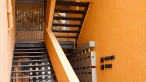 Eine Treppe mit Metallgeländern, einer gelben Wand und rechts angebrachten Stromkästen.