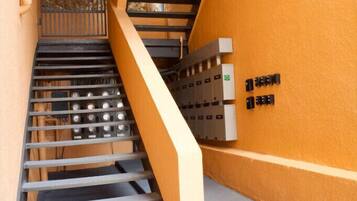 A staircase with metal railings, a yellow wall, and electrical boxes on the right.