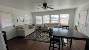 Ein Wohnzimmer mit einer Couch, einem Esstisch und einem Deckenventilator.