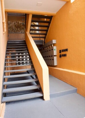 A staircase with a metal railing, a wall-mounted electrical panel, and a concrete floor. - Walk to Ferry • Red Hook 1BR Condo w/ Stunning Balcony Views + Free Parking (Red Hook)