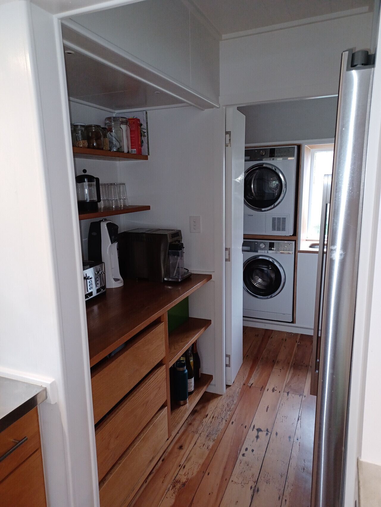 Eine kleine Küche mit Holzböden, einer Kaffeemaschine, einem Toaster und einer Waschmaschine.