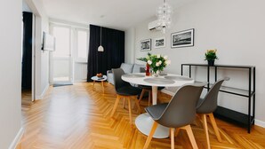 A modern dining area with a round table, grey chairs, and a pendant light. - Shortstaypoland Mokotowska (Warsaw)