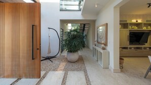 Ein modernes Interieur mit einer Holztür, einem Blumentopf, einer Treppe und einem Fernseher in einem Holzschrank.