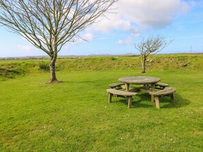 A picnic table in a grassy field with trees and a clear sky. - Park Hall Cottage (Haverfordwest)