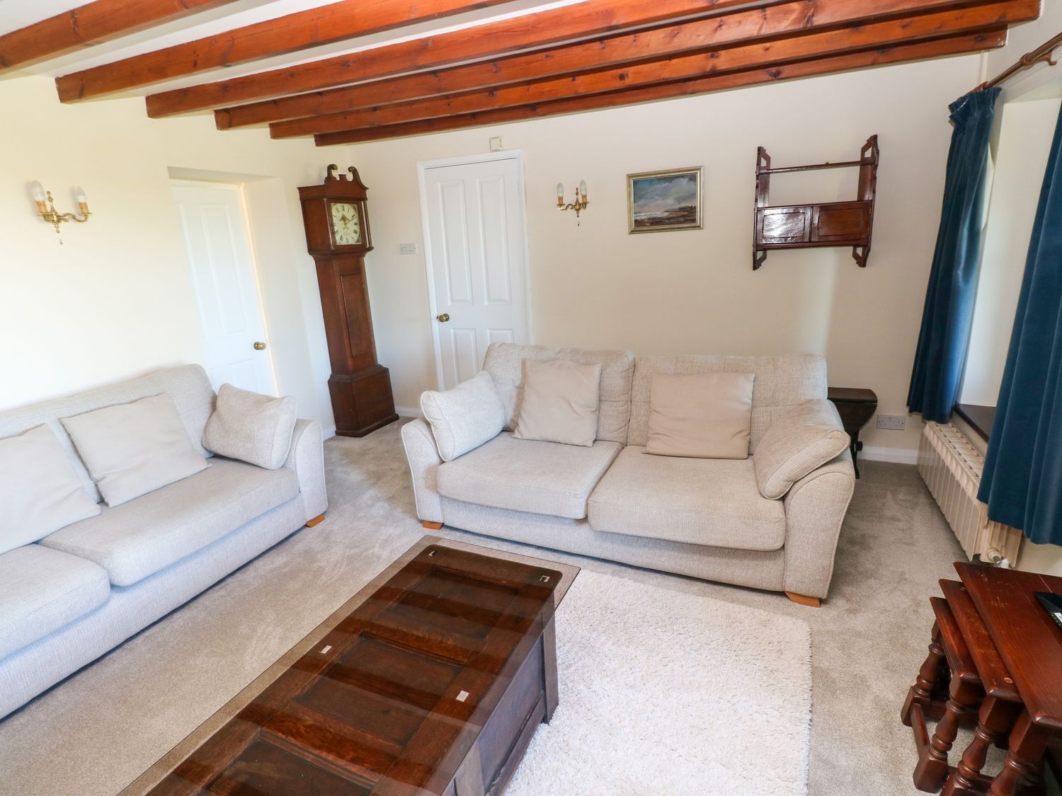 A living room with two sofas, a wooden coffee table, a clock, and a picture on the wall.