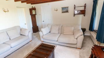 A living room with two sofas, a wooden coffee table, a clock, and a picture on the wall.