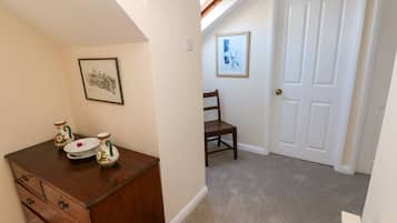 A room with a wooden dresser, a chair, a white door, and a framed picture on the wall.