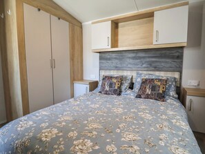 Un dormitorio con cama, armario y mesita de noche.