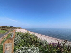Une route côtière menant à une plage, avec un ciel dégagé.