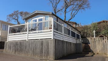 A wooden decked building with a balcony, a fenced area, and a clear sky.