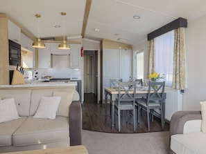 Une cuisine moderne avec des meubles blancs, un coin repas avec une table et des chaises, et un salon confortable avec un canapé.