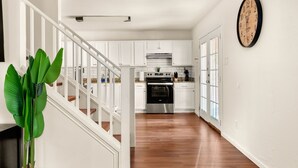 Une cuisine moderne avec des meubles blancs, des appareils en acier inoxydable et un escalier en bois.