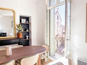 Une pièce moderne comprenant une table à manger, des chaises, un grand miroir et une vue sur un bâtiment, visible à travers une porte ouverte.
