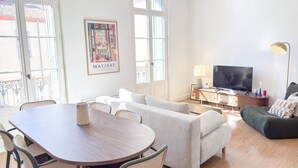 Uma sala de estar moderna com área de refeições, televisão e uma janela grande.