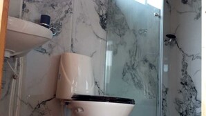 Une salle de bain avec des toilettes, un lavabo et une douche.
