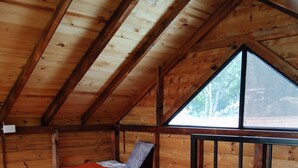 Une cabine avec deux lits, un plafond en pente et une fenêtre.