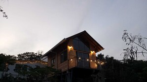 Une cabane en bois dotée d’un balcon, de grandes fenêtres et de guirlandes lumineuses.