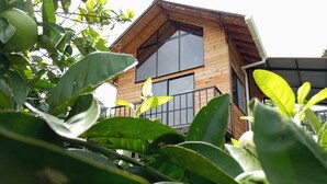 Une cabane en bois dotée de grandes fenêtres et d’un balcon.