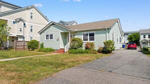 A residential street with houses, a red car parked on the street, and a clear blue sky. - Family Beach House · Sleeps 6 · 2 Blks · 6 Parking (Virginia Beach)